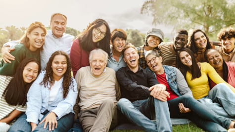 A group of adults of mixed ages and races sat together smiling and laughing towards the camera