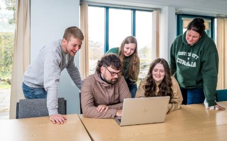 Students grouped around a laptop