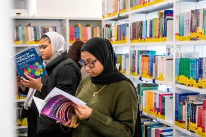 2 students in a library browsing books