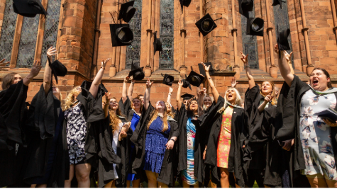 Students in graduation gowns tossing their caps