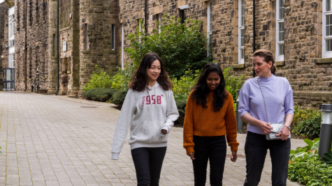 Three adult friends walking through campus together