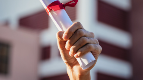 A hand holding a rolled up certificate