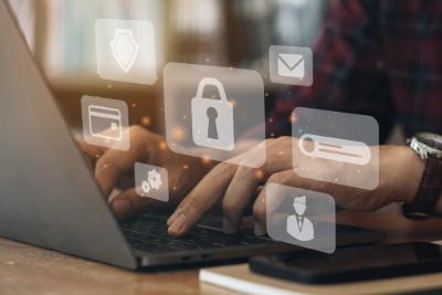 An image of a person typing on a laptop with security logo's overlayed.