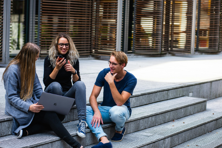 Three students sitting on steps outside of a university building