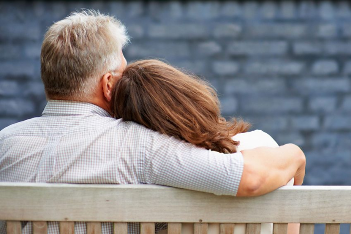 The image shows the back of a woman leaning on a man's shoulder
