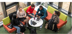 Group of university students socialising and studying together in a bright campus social space.