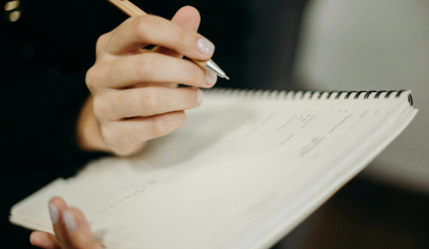A hand writing in a notebook, recording a conversation