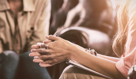 Two adults in a counselling room taking notes.