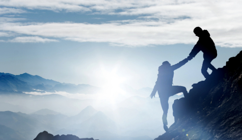 Two adults supporting each other climbing a mountain