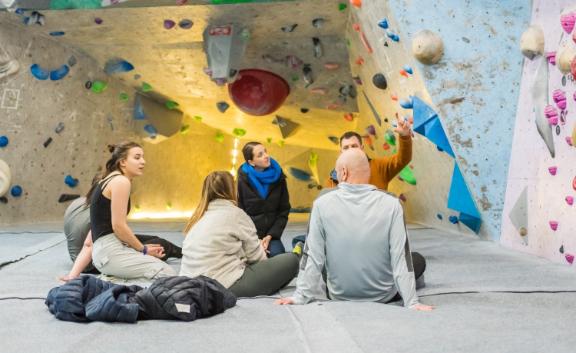 Climbing for wellbeing 2024 1, Students and staff sat at the climbing wall