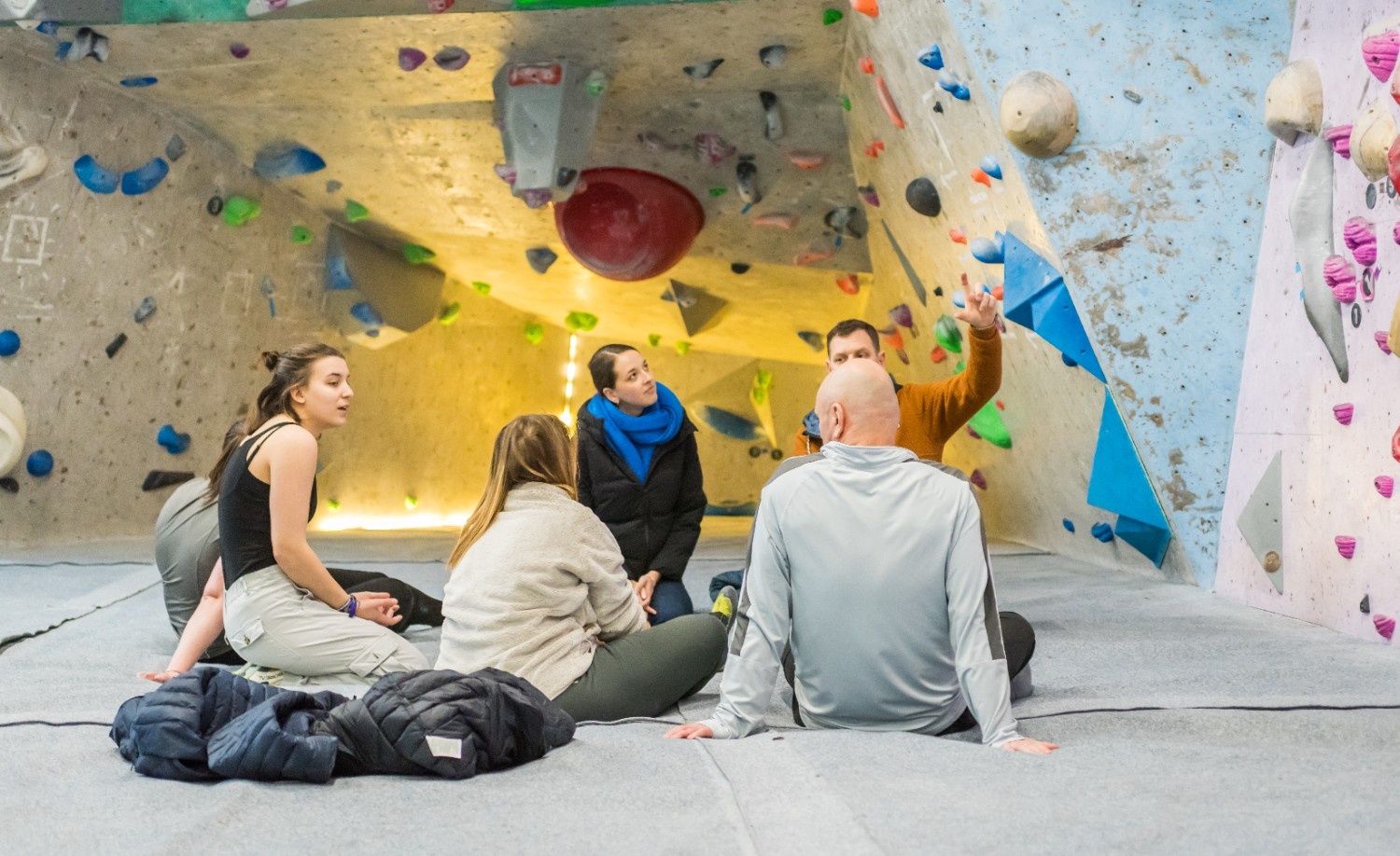 Climbing for wellbeing 2024 1, Students and staff sat at the climbing wall