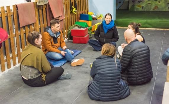 Climbing for wellbeing 2024 2, Students and staff at the climbing wall. They are sat in a circle having a discussion
