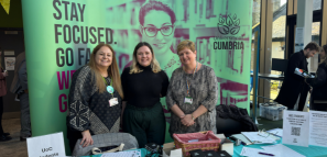 The image shows three staff members stood at a help desk for the careers team
